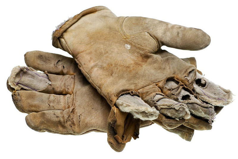 Worn leather work gloves showing signs of damage, emphasizing the need for proper maintenance.