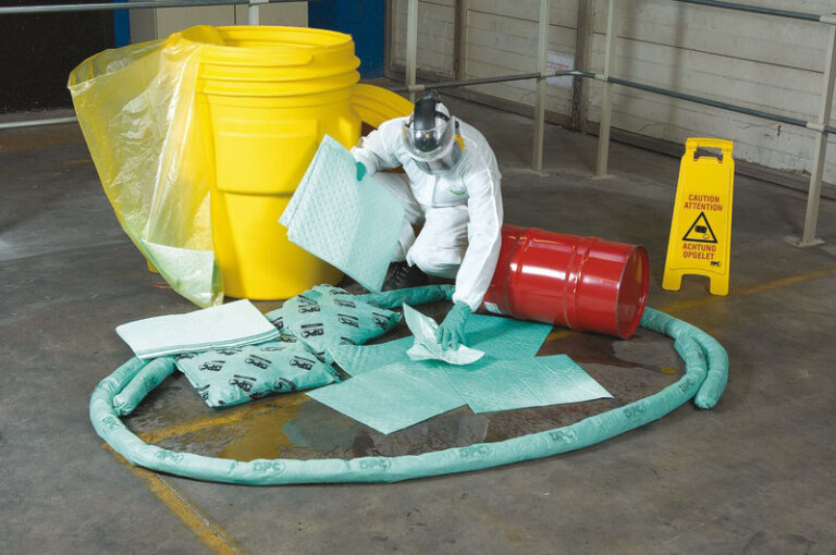 A worker using an oil absorbent product to manage a spill.