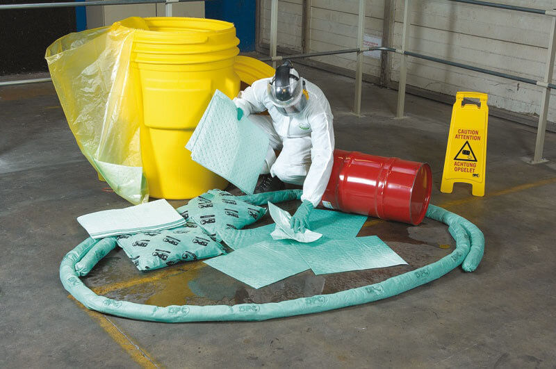 A worker using an oil absorbent product to manage a spill.