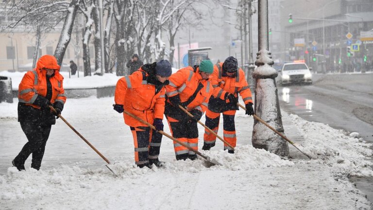 Workers in reflective winter PPE ensuring safety while clearing snow