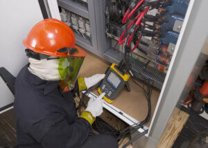 Worker wearing full PPE, including insulated gloves, face shields, while performing electrical operations to prevent electrical hazards.